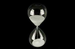 an hourglass with sand on a black background photo