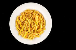 a white plate filled with pasta on a black background photo