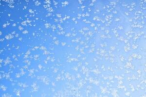 Abstract winter background. Frost on a frozen window against the blue sky. photo