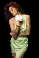 Smiling young woman with tattoo on arms showing pair of aces photo