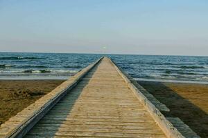 a wooden pier leads to the ocean photo