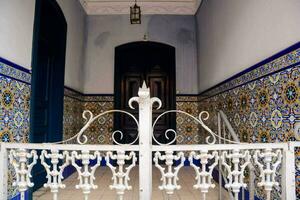 a white wrought iron fence in front of a tiled entrance photo