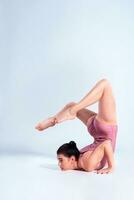 Flexible girl gymnast in beige leotard is performing complex elements of gymnastics while posing isolated on white background. Close-up. photo