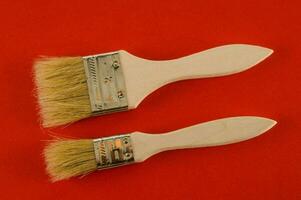 two paint brushes on a red surface photo