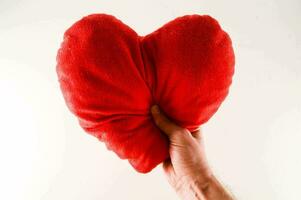 a person holding a red heart shaped pillow photo