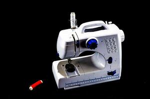 un de coser máquina con un rojo carrete de hilo foto