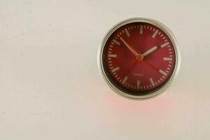 a red clock on a white wall photo