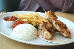 Chicken skewers with french fries and rice photo