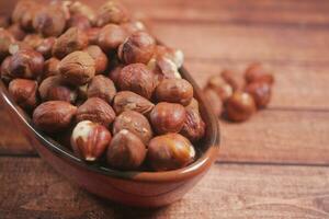 hazelnuts in a container on wooden background, photo