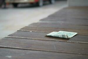 left one dollar cash on park bench photo