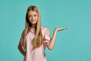 Studio portrait of a beautiful girl blonde teenager in a pink t-shirt posing over a blue background. photo