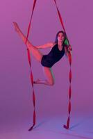 hermosa niña en un negro traje de baño es ejecutando un acrobático elementos en estudio. foto