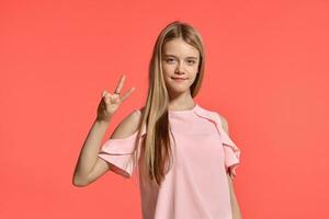 Studio portrait of a beautiful girl blonde teenager in a rosy t-shirt posing on pink background. photo