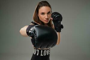 Athletic woman in boxing gloves is practicing karate in studio. photo