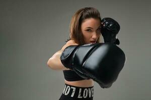 atlético mujer en boxeo guantes es practicando kárate en estudio. foto