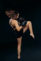 Athletic woman in boxing gloves is practicing karate in studio. photo