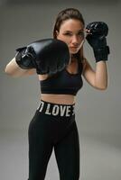 Athletic woman in boxing gloves is practicing karate in studio. photo