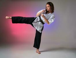 atlético mujer en tradicional kimono es practicando kárate en estudio. foto