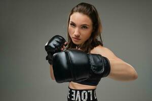 Athletic woman in boxing gloves is practicing karate in studio. photo