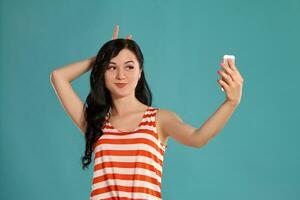 Studio photo of a gorgeous girl teenager posing over a blue background.