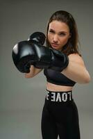 Athletic woman in boxing gloves is practicing karate in studio. photo