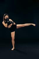 Athletic woman in boxing gloves is practicing karate in studio. photo