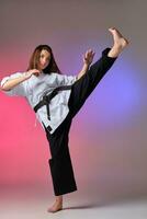 atlético mujer en tradicional kimono es practicando kárate en estudio. foto