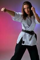 Athletic woman in traditional kimono is practicing karate in studio. photo