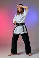 Athletic woman in traditional kimono is practicing karate in studio. photo