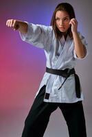 Athletic woman in traditional kimono is practicing karate in studio. photo