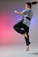 Athletic woman in traditional kimono is practicing karate in studio. photo