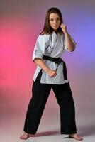 Athletic woman in traditional kimono is practicing karate in studio. photo
