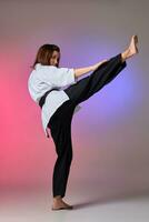 Athletic woman in traditional kimono is practicing karate in studio. photo