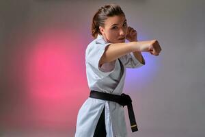 atlético mujer en tradicional kimono es practicando kárate en estudio. foto