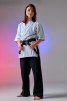 Athletic woman in traditional kimono is practicing karate in studio. photo