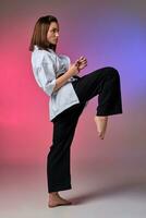 Athletic woman in traditional kimono is practicing karate in studio. photo