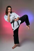 Athletic woman in traditional kimono is practicing karate in studio. photo