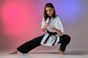 Athletic woman in traditional kimono is practicing karate in studio. photo