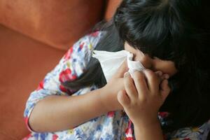 Sick child with flu blow nose with napkin. photo