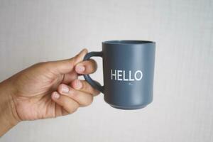 hand holding a blue coffee cup with hello word photo