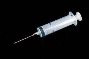 a syringe with a needle on a black surface photo