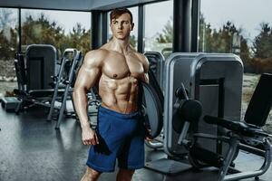 Handsome man with big muscles, posing at the camera in the gym photo