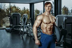 sexy muscular hombre posando en gimnasia, conformado abdominal. fuerte masculino desnudo torso abdominales, trabajando fuera foto