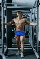 hermoso hombre con grande músculos, posando a el cámara en el gimnasio foto