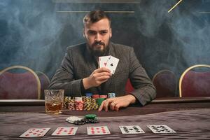 hermoso barbado hombre es jugando póker sentado a el mesa en casino. foto