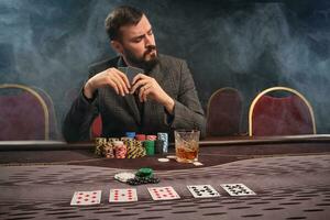 hermoso barbado hombre es jugando póker sentado a el mesa en casino. foto