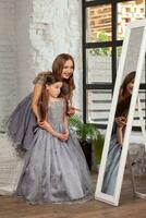 Indoor portrait of a beautiful mother with her charming little daughter posing against bedroom interior. photo