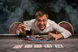 Handsome emotional man is playing poker sitting at the table in casino. photo