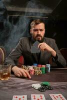 Handsome bearded man is playing poker sitting at the table in casino. photo