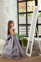interior retrato de un pequeño encantador niña vistiendo en un hermosa vestido. foto